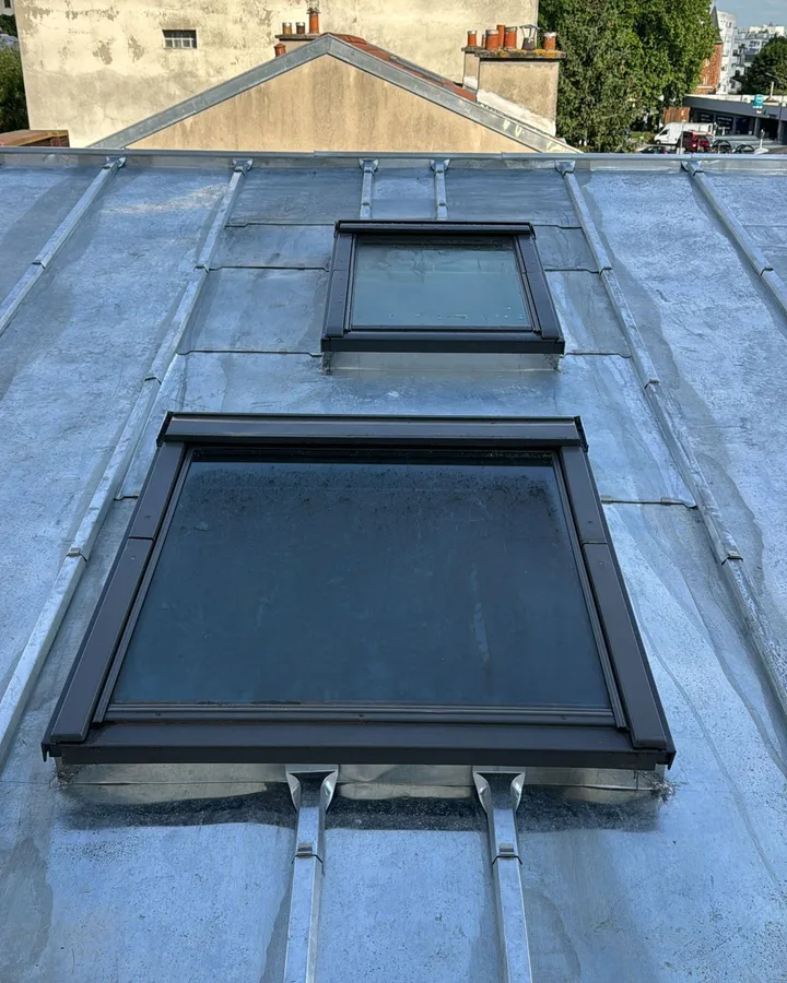 Terrasson en zinc naturel à joint debout avec deux fenêtres de toit encastrées et leurs solins, sur un immeuble du Val-de-Marne.