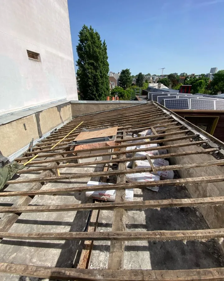 Le même versant avant travaux : voliges grises fendues et liteaux vermoulus laissant voir le support dégradé de l'ancienne couverture.